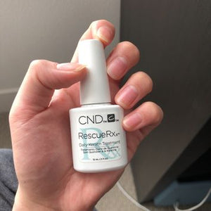 Hand holding a bottle of CND Rescue Rxx to repair nails