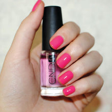 Load image into Gallery viewer, Hand with pink nail polish holding a bottle of CND Super Shiney Top Coat
