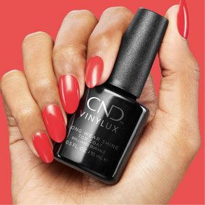 Hand with red nail polish holding a bottle of CND Vinylux Long Wear Shine Top Coat